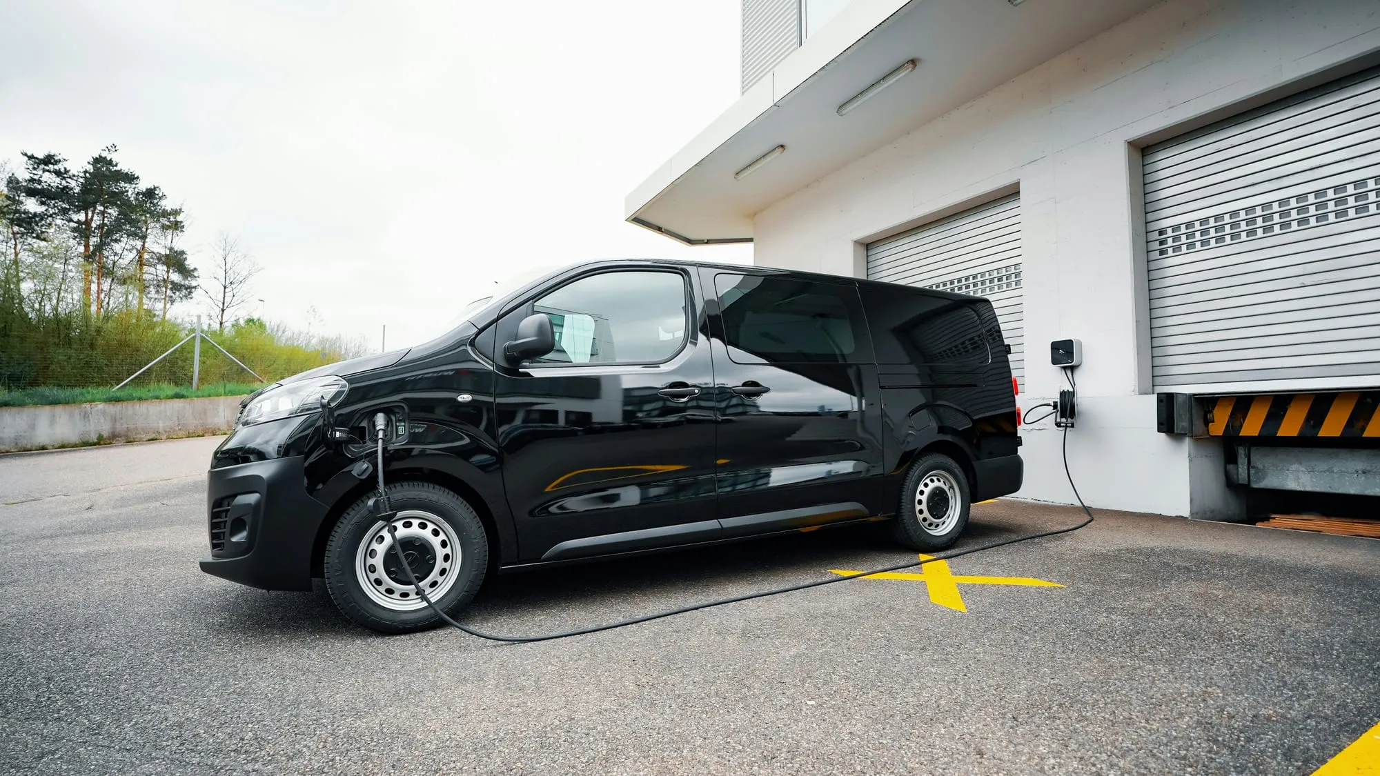 Utilitaire électrique en charge sur une borne murale, dans la cour d'un bâtiment professionnel